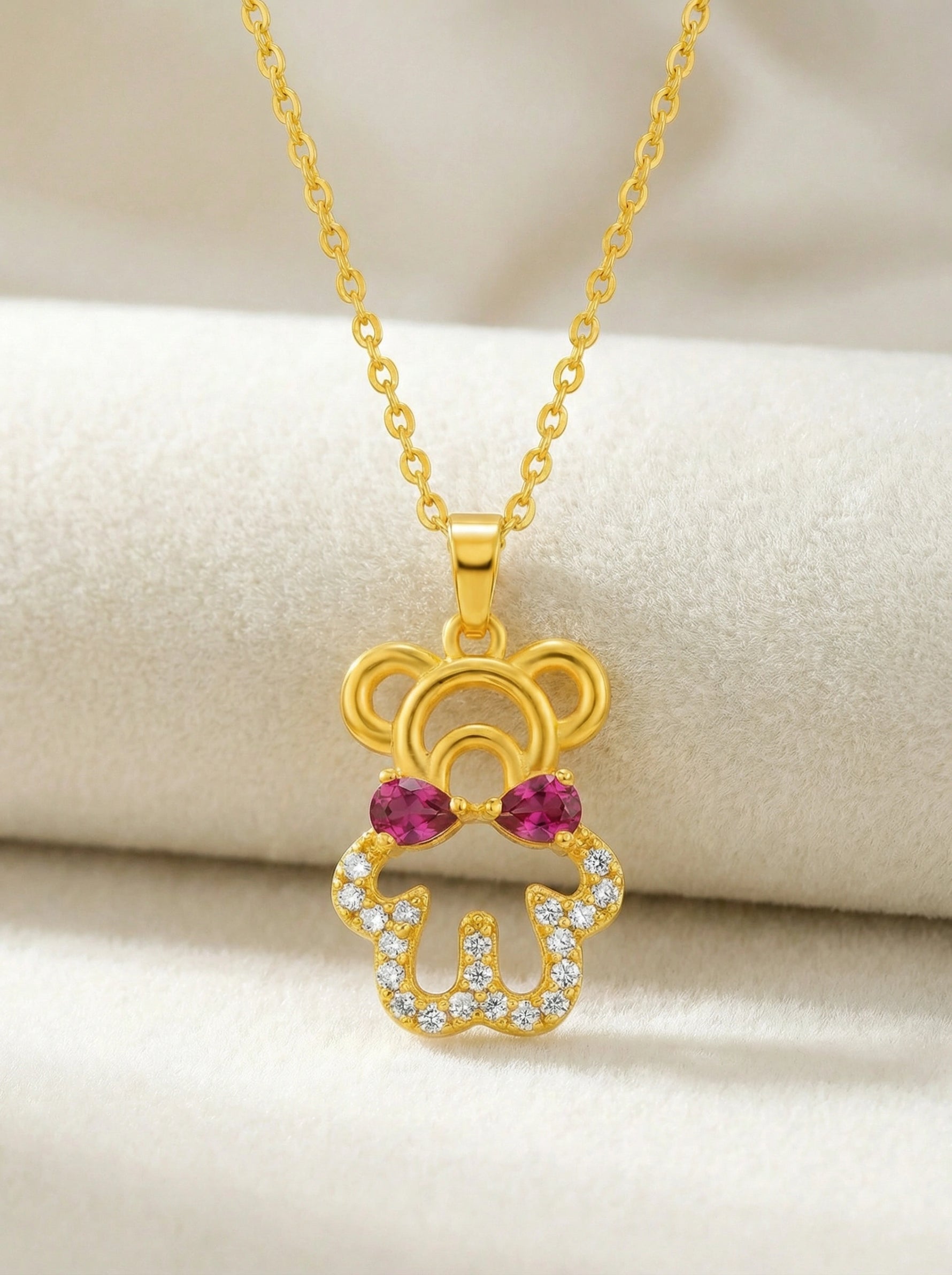 18k Gold plated pendant with red gemstones on a beige background