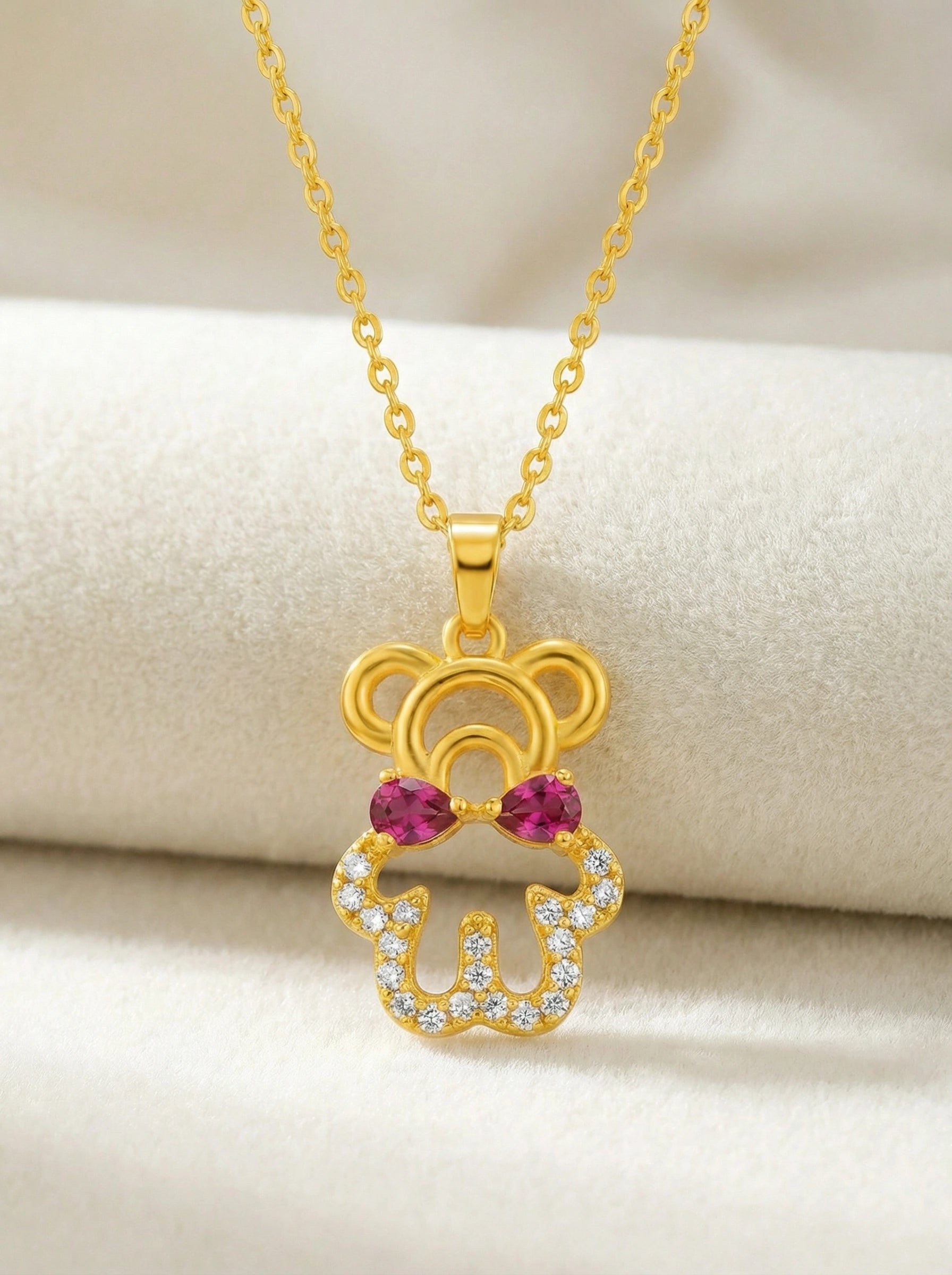 18k Gold plated pendant with red gemstones on a beige background