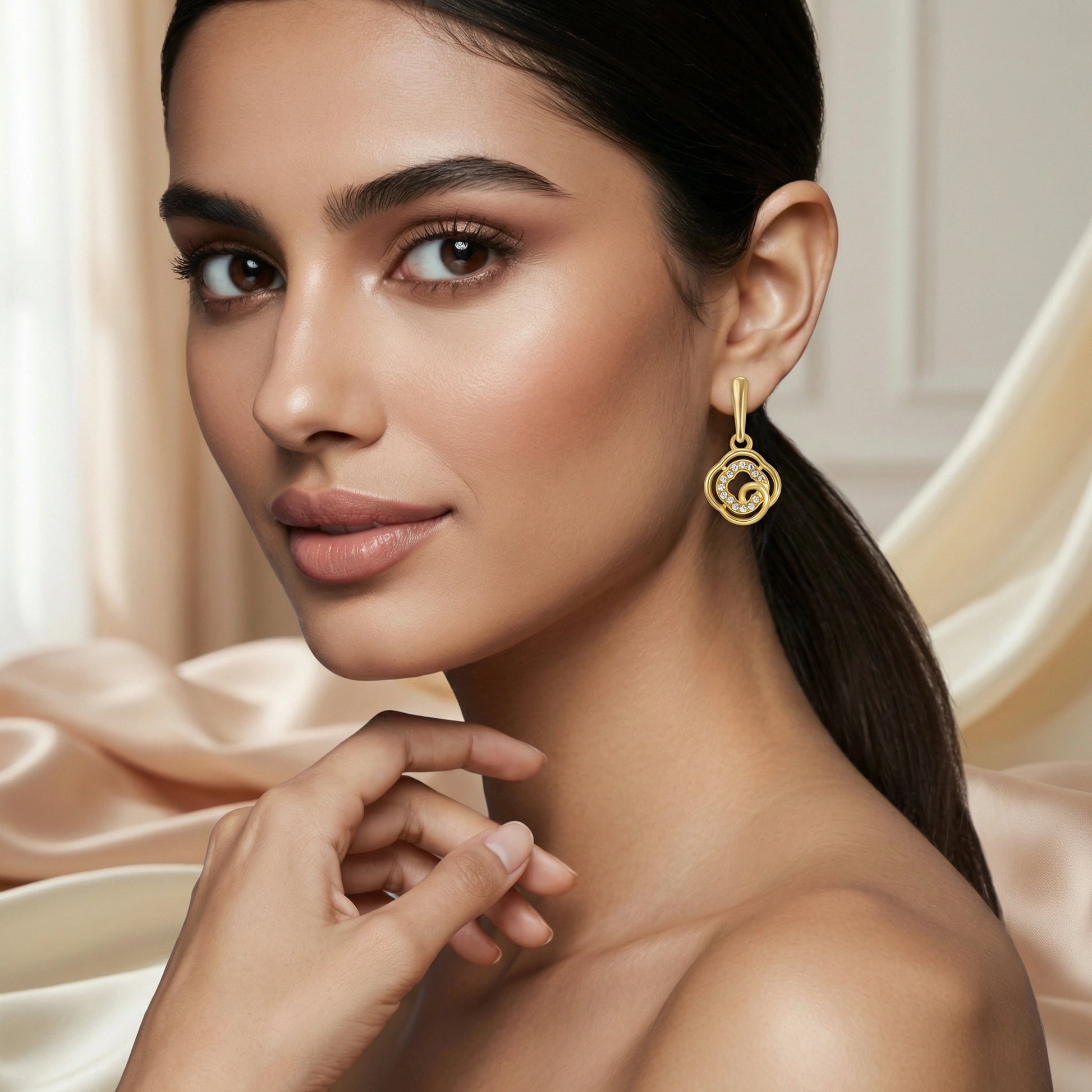 Woman wearing 18k  gold plated earrings with a neutral background