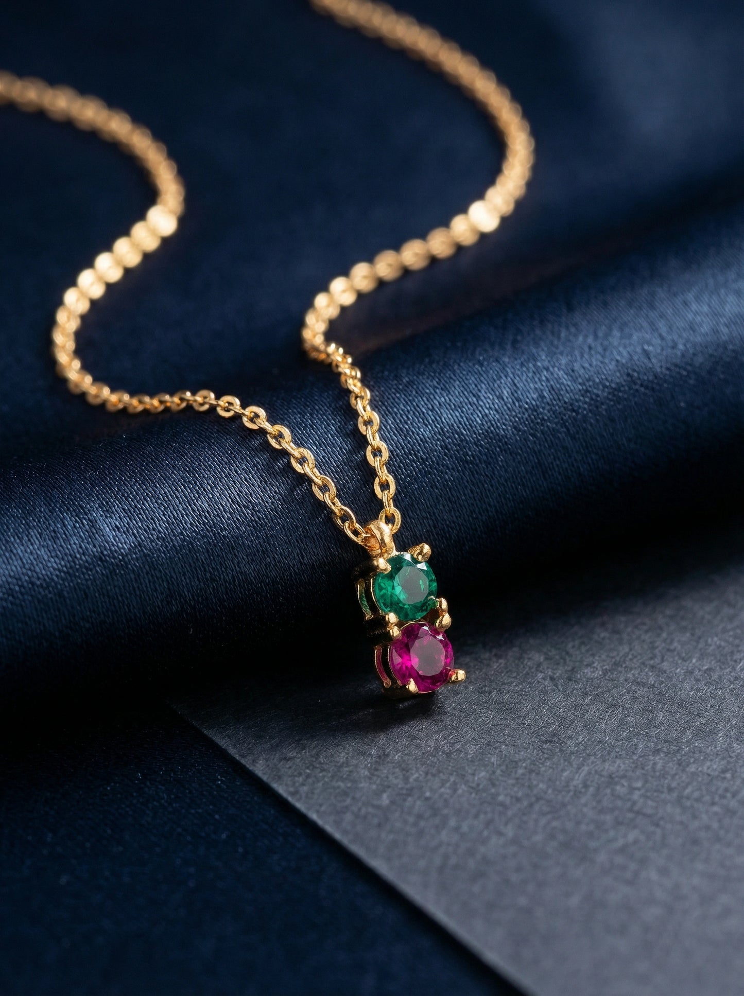 18k gold plated necklace with gemstone pendant on a dark blue fabric background