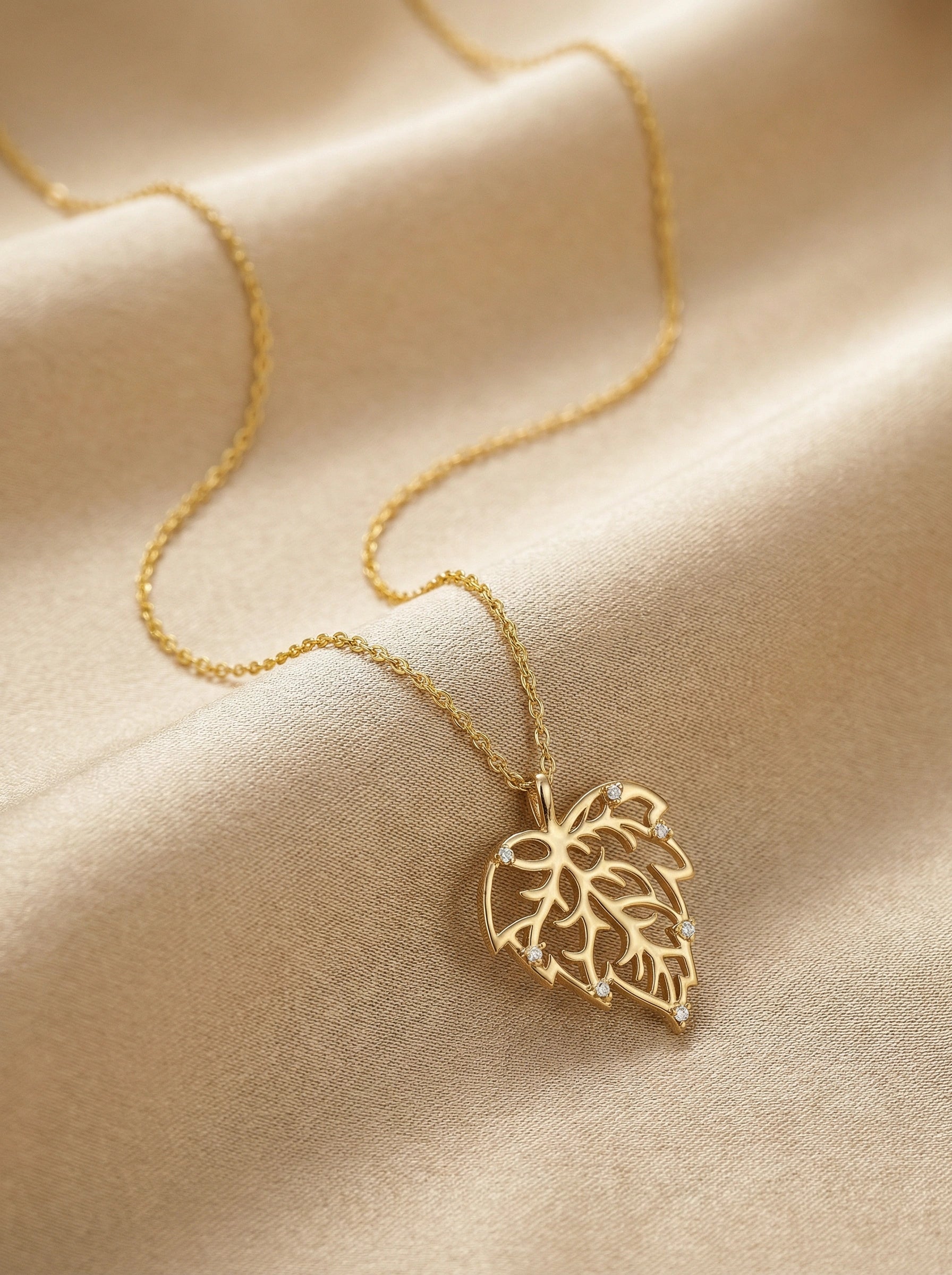 18k Gold plated necklace with a leaf pendant on a beige fabric background