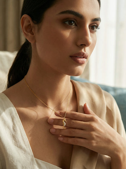 Woman wearing 18k gold plated  necklace with a pendant, holding it close to her chest.
