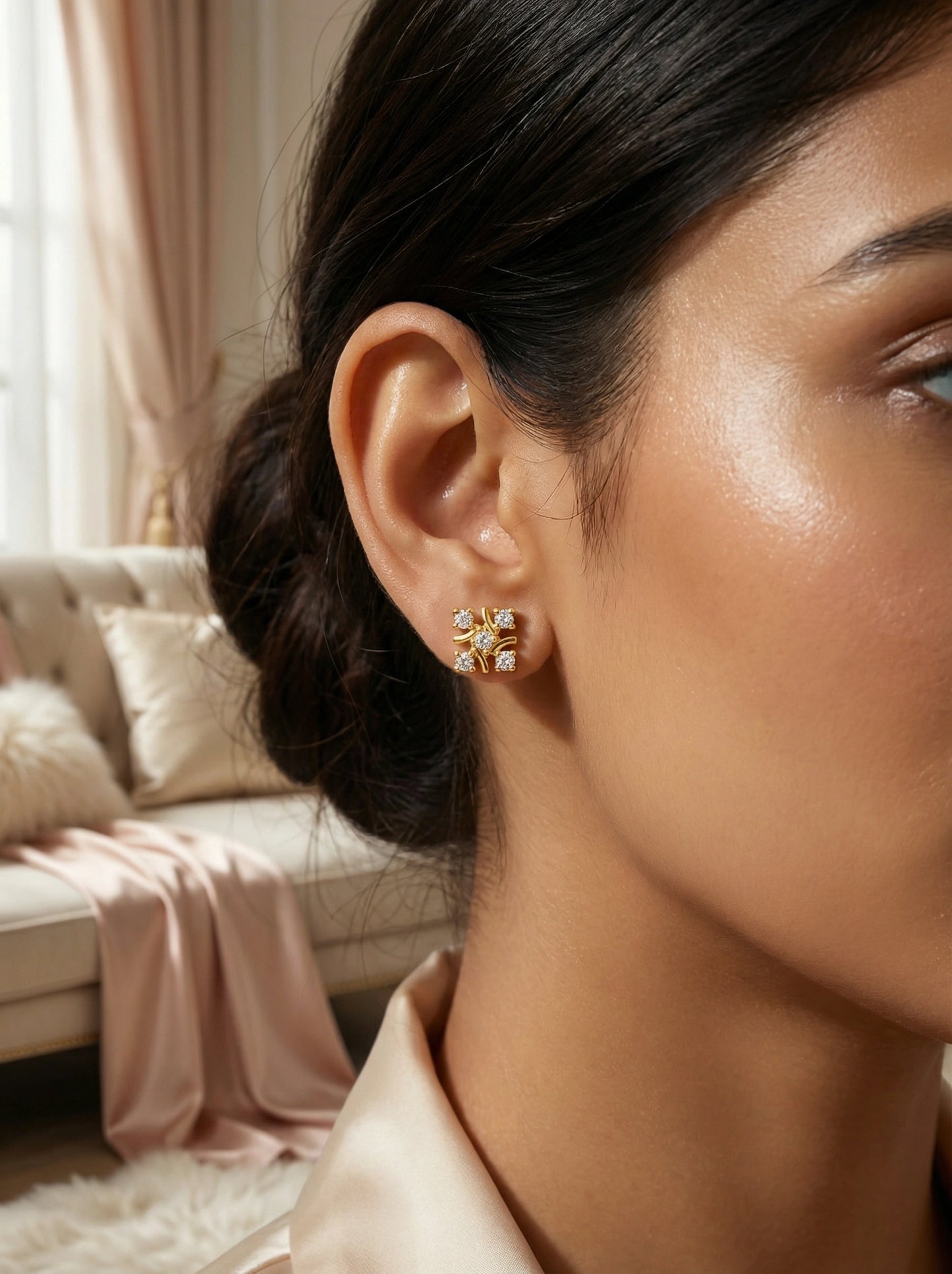 close-up of a woman wearing 18k  gold plated earrings with a blurred indoor background