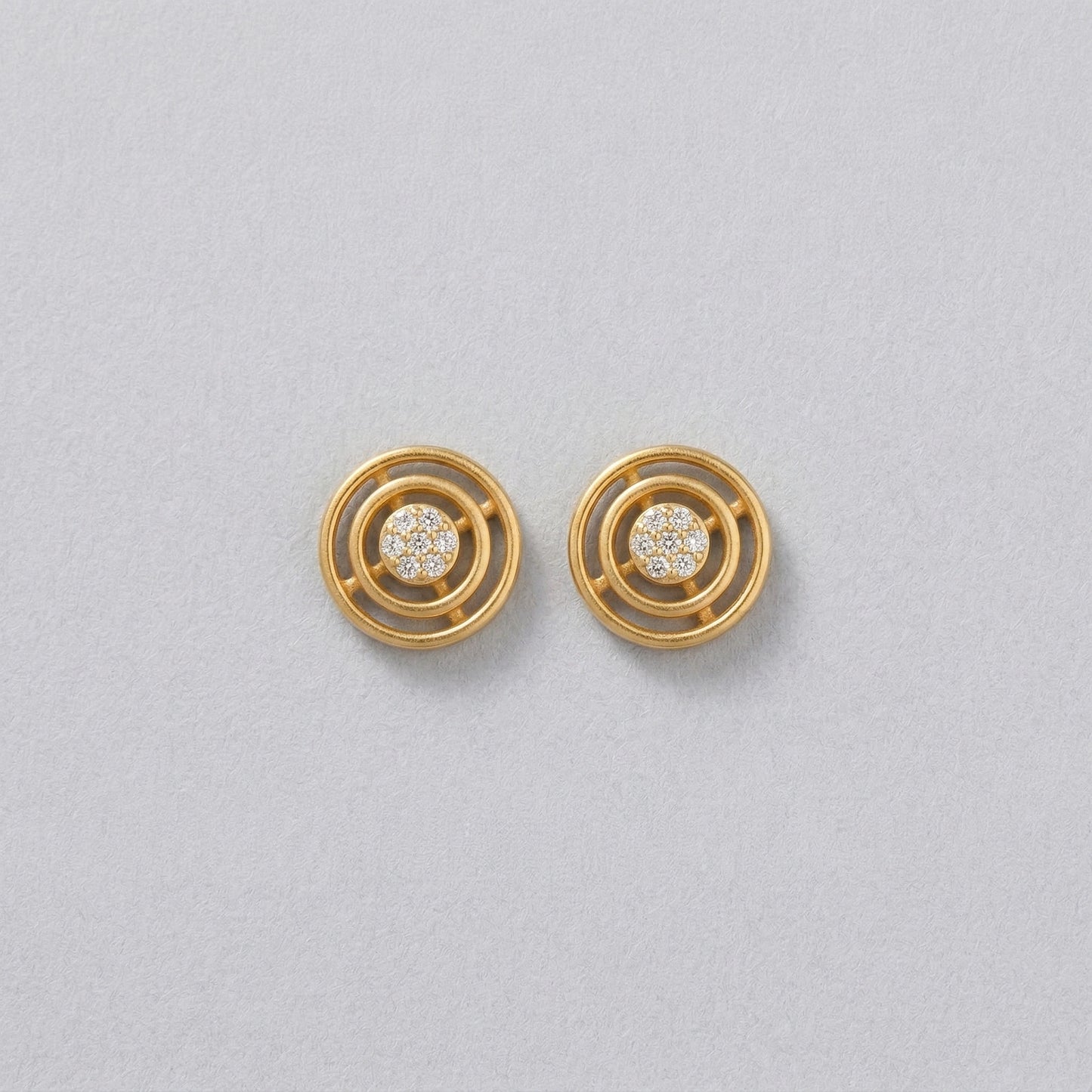 18k gold plated earrings with circular design on a light gray background