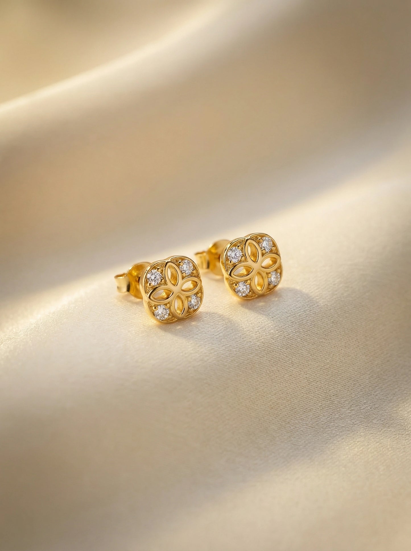 18k gold plated earrings with diamond accents on a beige background