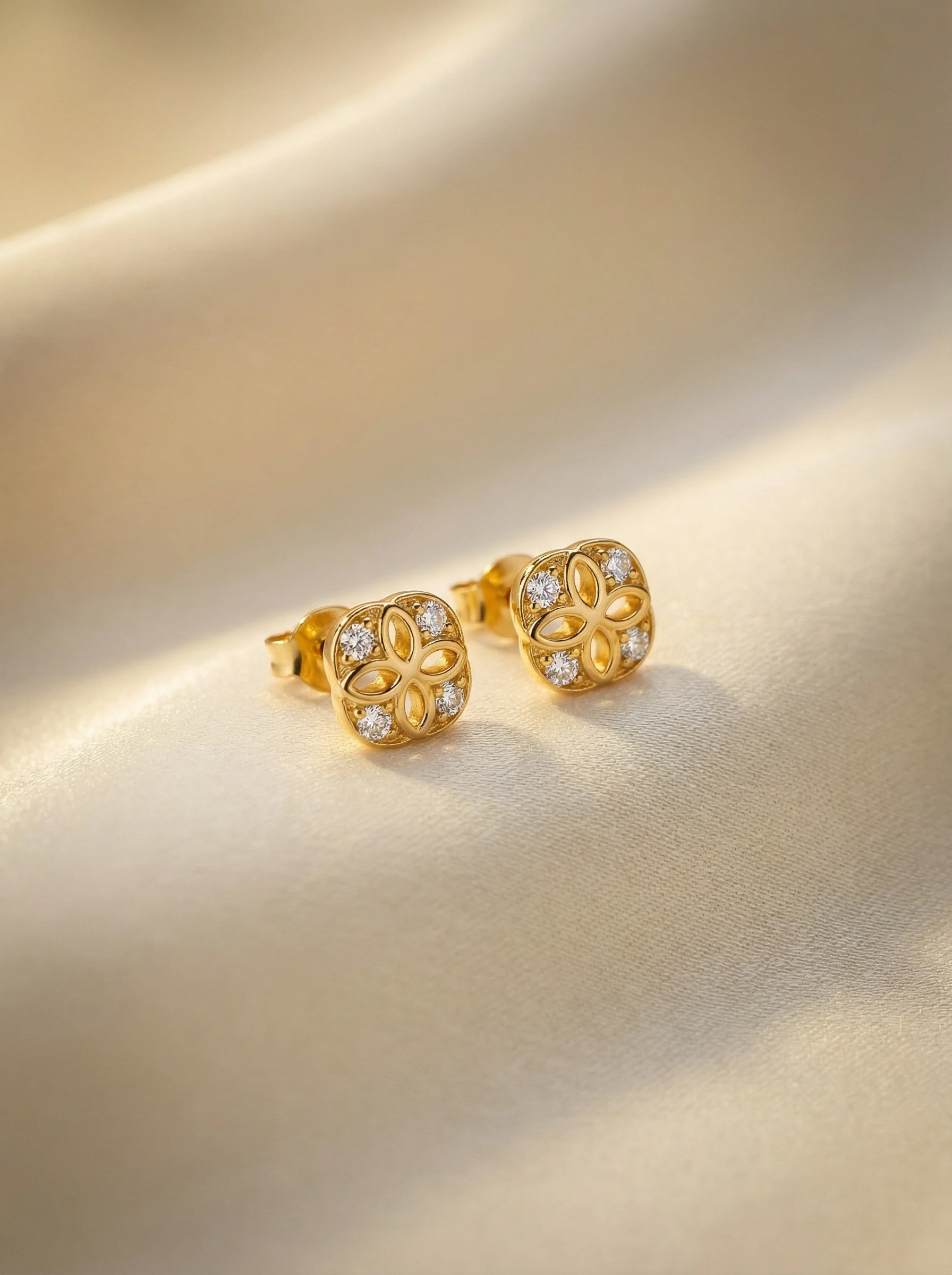 18k Gold plated earrings with diamond accents on a beige background