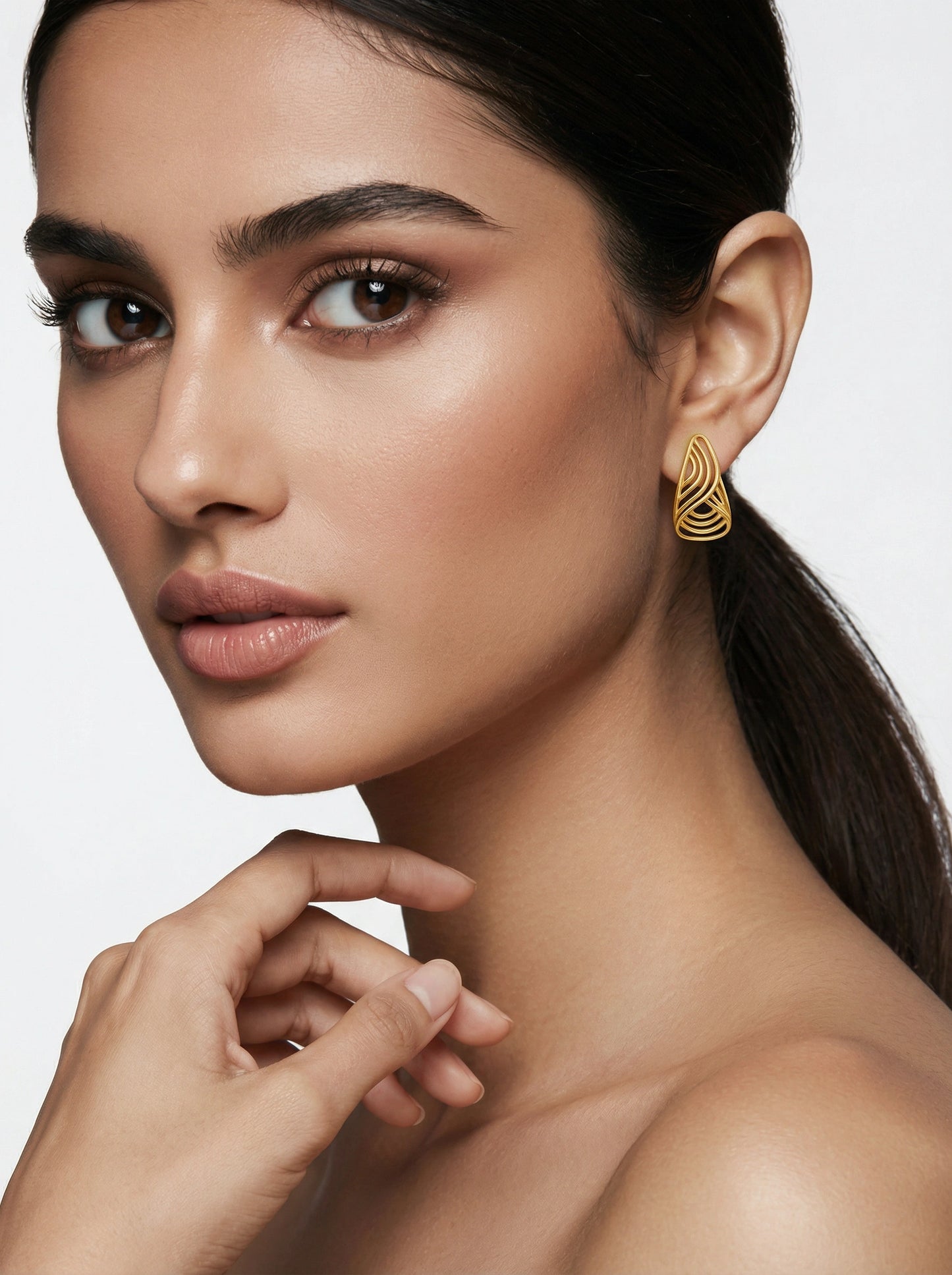 close-up of a woman wearing 18k gold plated earrings with a neutral background